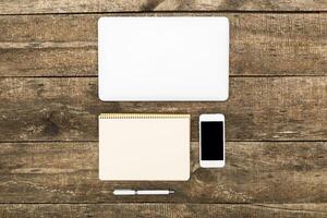 Workspace setup featuring a laptop, notebook, phone, and pen on a wooden table photo