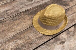 Stylish yellow fedora hat resting on rustic wooden surface in a warm light setting photo
