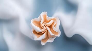 A delicate, handcrafted flower made of soft fabric resting on a smooth, light blue backdrop photo