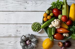 menu or program, roulette, water, dumbbells and diet food from fresh fruits on a white background, the concept of weight loss and detoxification, top view photo
