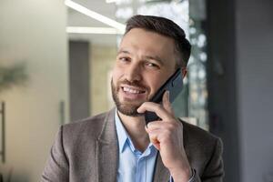 Smiling business professional in a modern office environment having a phone conversation on a smartphone. photo