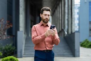 Serious thoughtful man thinks while reading emails, businessman walks with smartphone in hands uses messaging app. photo