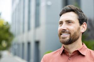 Close-up photo of successful businessman smiling and looking to the side. Man outside office building dreaming and thinking, satisfied with successful results of achievement