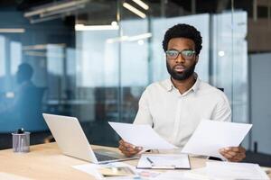 Portrait of serious focused financier accountant doing paperwork, man holding financial reports in hands looking at camera, businessman doing paperwork, filling and checking tax forms, contracts. photo