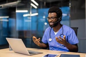 Successful experienced doctor with headset and laptop inside office at workplace working remotely. Man consulting patients, helping and supporting, call, remote meeting conference. photo