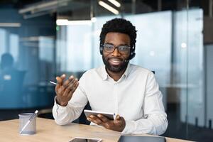 Webcam view, man with headset looking into camera, talking to colleagues and partners remotely using call. Smiling and friendly online customer support worker. photo