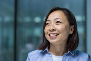 A smiling Asian businesswoman showcasing confidence and positivity in a modern professional setting. Her bright expression promotes a sense of success, motivation, and empowerment photo