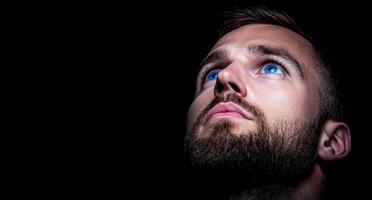Man looking up with blue eyes in the dark photo