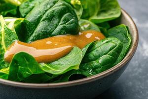 Fresh spinach salad with vinaigrette dressing in a bowl. photo