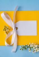 A picture of a blank card with a yellow ribbon and white flowers photo