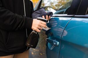 person is shown cleaning a blue car with a spray bottle and a cloth photo
