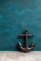 A bronze anchor against a textured blue wall photo