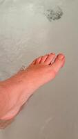 A close up of a Caucasian persons foot submerged in water, symbolizing relaxation and personal care photo