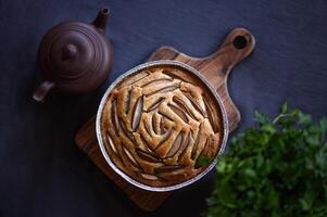 A fruit cake or a muffin or a pie with a clay pot and herbs. Flat lay. photo