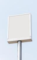 White mock up light box billboard on pole with blue sky background. Clipping path for mockup photo