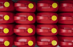 Top view of arranged red plastic motor oil bottles, containers with handle and yellow screw cap photo