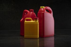 Front view of three different yellow and red plastic motor oil bottles, container with handle and screw cap without label photo