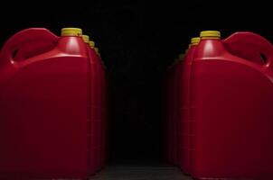 Front view of two columns of red plastic motor oil bottles forming a tunnel, containers with handle and yellow screw cap without label photo