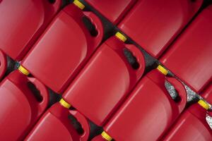Texture of red plastic motor oil bottles, containers with handle and yellow screw cap photo