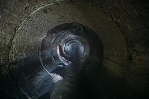 Inside underground urban sewer system. Sewage flowing in round sewer pipe photo