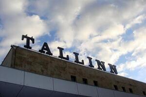 Low-angle shot of the Tallinn inscription on top of railway building. Close-up of the word Tallinn in large, bold letters on a building rooftop on an old building railway station against a cloudy sky photo