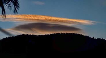 A cloud is seen in the sky over a mountain photo