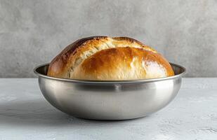 Freshly baked sourdough loaf in rustic metal bowl on concrete photo