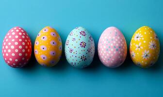 A row of painted eggs with different colors and patterns. The eggs are arranged in a line on a blue background photo