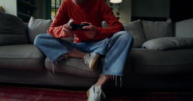 A young woman in everyday ojeda plays games using a joystick while sitting on the couch at home. The moves from the carpet to the woman's face video