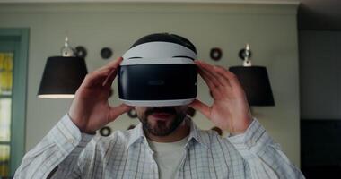 A stylish man in casual clothes takes off a virtual reality headset and looks into the camera with a smile, front view video