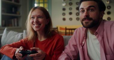A man and a woman play games sitting on the couch at home and using joysticks. Close-up of laughing faces video