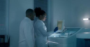 Work in a medical laboratory. A man and a woman in lab coats are setting up a blood splitting machine and talking video