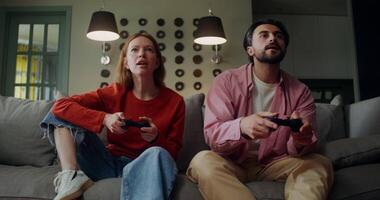 A man and a woman play games with a joystick while sitting on the couch with a concentrated look, and then the woman wins video