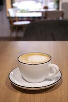 Cafe. Cup of cappuccino on the table. Hot coffee drink. White cup and saucer. photo