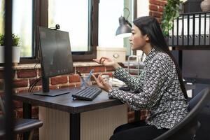 Young businesswoman hosting videoconference with client, working on marketing strategies and project execution. Female manager collaborating remotely with male coworker on startup company plans. photo