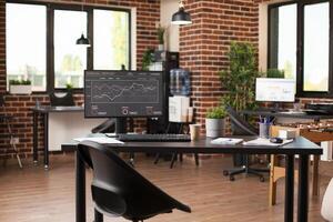 Empty yet inviting workspace containing computer with company growth presentation on screen. Brick wall room is furnished with modern furniture vibrant plants and foosball table for refreshment. photo