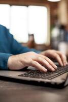 Closeup of caucasian person typing on laptop on desk in startup office. Selective focus on hands of employee updating company research information on digital device, using modern technology at work. photo