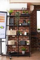 Office cabinet arranged with plant decorations and boxes as digital screen displays summary of business analytics. Modern workspace containing well organized shelf positioned at brick wall. photo