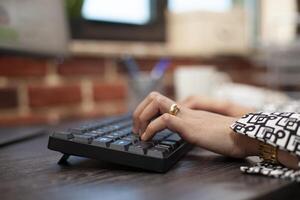 Closeup on the hands of a business person using keyboard on office desk. Female professional typing in data and updating company project plan on computer in modern workspace. photo