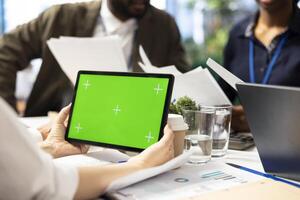 Organizational staff looking at device with green screen during a meeting, ensuring progress for an expansion project. Professional forecast affiliates sharing ideas for data management. photo