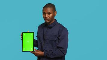 Security guard holding clock, rushing people out of property. Portrait of stern bodyguard showing visitors time is passing, preparing for closing down location, studio background, camera A photo