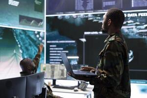 Military staff in high tech command post work on data integration, processing real time surveillance footage and maintaining security protocols. National defense in an army base of operations. photo