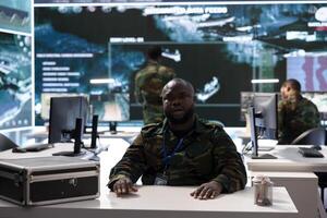Military intelligence expert conducts a strategic teleconference connection in a modern command post, utilizing real time data on multiple screens for effective communication and decision making. photo