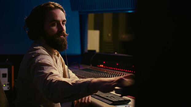 Audio expert operating motorized faders and mixing console in control room, using sliders and switchers buttons to edit and process sounds. Music designer and producer recording tracks. Camera B. photo