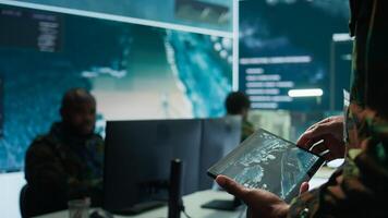 Military officer leads cybersecurity operations in a high tech operation room command post, ensuring data protection. Soldiers working with cctv surveillance systems, satellite imagery. Camera B. photo
