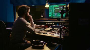 Music producer fixing coiled cable inside amplifier or audio compressor, prepares control room technical equipment for a recording session. Sound engineer works on producing tracks. Camera B. photo