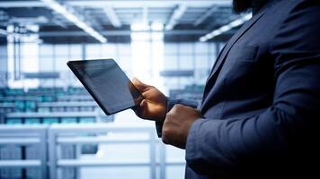 Engineer in high tech facility using tablet to patch network issues leading to slow data transfer rates. Close up of worker fixing errors affecting servers performance and connectivity, camera B photo