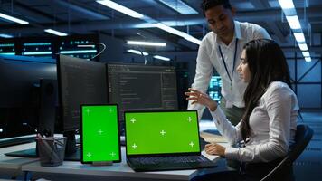 Engineer working with mockup laptop and tablet in data center used for managing gear energy consumption. Employee using green screen devices in workplace used for automation in server farm, camera B photo