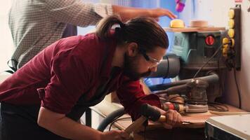 Man carving intricate designs into wood using chisel and hammer in carpentry shop, enjoying diy hobby. Woodworking specialist in studio shaping wooden pieces with tools, making wood art, camera A photo