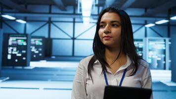 Engineer in high tech data center managing and maintaining databases, ensuring data integrity, security and availability. Indian woman updating server room supercomputers systems, camera B photo